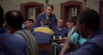 Movie still from “In the Name of the Father” (1993), directed by Jim Sheridan – A group of men sitting around a table; Medium shot, Over the shoulder angle