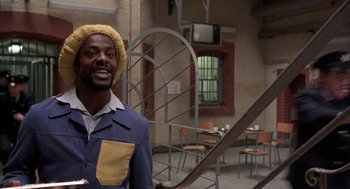 Movie still from “In the Name of the Father” (1993), directed by Jim Sheridan – A man in a yellow hat standing next to a table; Medium shot, Low angle