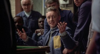 Movie still from “In the Name of the Father” (1993), directed by Jim Sheridan – An old man is sitting in front of a group of people; Medium shot, High angle