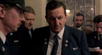 Movie still from “In the Name of the Father” (1993), directed by Jim Sheridan – A man in a suit and tie standing next to another man in a suit and tie; Close Up shot, Over the shoulder angle