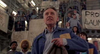 Movie still from “In the Name of the Father” (1993), directed by Jim Sheridan – An older man in a blue jacket is holding a book; Medium shot, Low angle