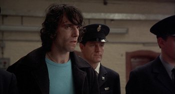 Movie still from “In the Name of the Father” (1993), directed by Jim Sheridan – A man in a blue shirt is standing next to a man in a uniform; Close Up shot, Low angle