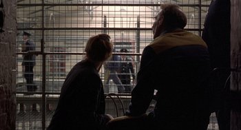 Movie still from “In the Name of the Father” (1993), directed by Jim Sheridan – A man and a woman sitting in front of a cage; Medium shot, Over the shoulder angle