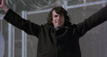 Movie still from “In the Name of the Father” (1993), directed by Jim Sheridan – A man with long hair and a black coat; Medium shot, Low angle