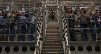 Movie still from “In the Name of the Father” (1993), directed by Jim Sheridan – A group of people standing on top of a metal staircase; Wide shot, Overhead angle