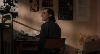 Movie still from “In the Name of the Father” (1993), directed by Jim Sheridan – A man sitting at a desk in a room; Medium shot, Low angle