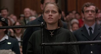 Movie still from “In the Name of the Father” (1993), directed by Jim Sheridan – A woman with a cross on her neck in a courtroom; Close Up shot, Low angle