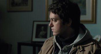 Movie still from “Incendies” (2010), directed by Denis Villeneuve – A man sitting in front of a wall with pictures; Close Up shot, Over the shoulder angle
