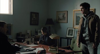 Movie still from “Incendies” (2010), directed by Denis Villeneuve – A woman sitting at a desk in a dark room; Wide shot, High angle