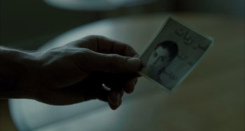 Movie still from “Incendies” (2010), directed by Denis Villeneuve – A person holding a picture of a man; Extreme Close Up shot, Over the shoulder angle