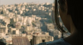 Movie still from “Incendies” (2010), directed by Denis Villeneuve – A woman looking out over a city from a balcony; Extreme Close Up shot, Over the shoulder angle