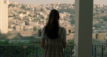 Movie still from “Incendies” (2010), directed by Denis Villeneuve – A woman standing on a balcony looking out over a city; Medium shot, Over the shoulder angle