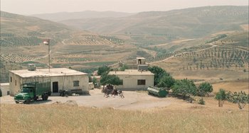 Movie still from “Incendies” (2010), directed by Denis Villeneuve – A group of people sitting on top of a dirt field; Extreme Wide shot, High angle