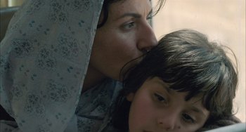 Movie still from “Incendies” (2010), directed by Denis Villeneuve – A woman and a child snuggled up to each other; Close Up shot, Low angle
