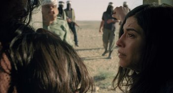 Movie still from “Incendies” (2010), directed by Denis Villeneuve – A group of people standing in the desert; Close Up shot, Over the shoulder angle