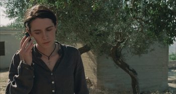 Movie still from “Incendies” (2010), directed by Denis Villeneuve – A woman wearing a black shirt standing next to a tree; Close Up shot, Over the shoulder angle