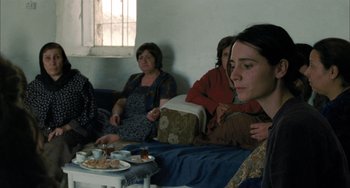 Movie still from “Incendies” (2010), directed by Denis Villeneuve – A group of people sitting around a table; Medium shot, Over the shoulder angle