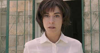Movie still from “Incendies” (2010), directed by Denis Villeneuve – A woman in a white dress shirt is looking at the camera; Close Up shot, Low angle