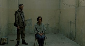 Movie still from “Incendies” (2010), directed by Denis Villeneuve – A man and a woman sitting on a chair in an empty room; Wide shot, Over the shoulder angle