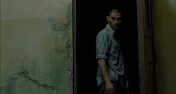 Movie still from “Incendies” (2010), directed by Denis Villeneuve – A man standing in front of a wall; Medium shot, Over the shoulder angle