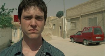Movie still from “Incendies” (2010), directed by Denis Villeneuve – A man standing on a street with his eyes wide open; Close Up shot, Low angle