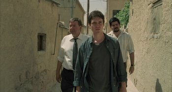 Movie still from “Incendies” (2010), directed by Denis Villeneuve – Three men are walking down the street together; Medium shot, Low angle