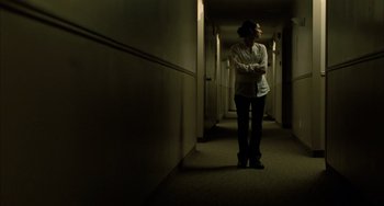 Movie still from “Incendies” (2010), directed by Denis Villeneuve – A woman standing in a hallway with her arms crossed; Wide shot, Low angle