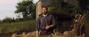 Movie still from “Far from the Madding Crowd” (2015), directed by Thomas Vinterberg – A man standing in front of a flock of sheep; Medium shot, Low angle