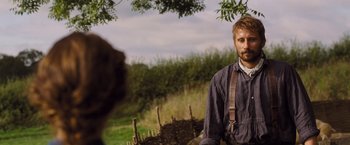 Movie still from “Far from the Madding Crowd” (2015), directed by Thomas Vinterberg – A man standing next to a dog in a field; Medium shot, Over the shoulder angle