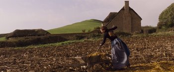 Movie still from “Far from the Madding Crowd” (2015), directed by Thomas Vinterberg – A woman is pushing a wheelbarrow in a field; Wide shot, Low angle