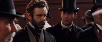 Movie still from “Far from the Madding Crowd” (2015), directed by Thomas Vinterberg – A man in a top hat standing next to another man in a suit; Close Up shot, Over the shoulder angle