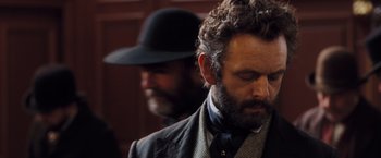 Movie still from “Far from the Madding Crowd” (2015), directed by Thomas Vinterberg – A man with a beard wearing a suit and a hat; Close Up shot, Over the shoulder angle