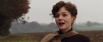 Movie still from “Far from the Madding Crowd” (2015), directed by Thomas Vinterberg – A young woman with short brown curly hair wearing a brown scarf; Close Up shot, Low angle
