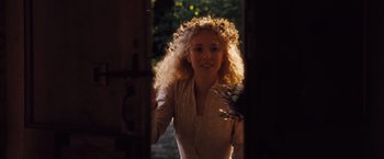 Movie still from “Far from the Madding Crowd” (2015), directed by Thomas Vinterberg – A woman with curly blonde hair standing in front of a door; Medium shot, Over the shoulder angle