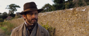 Movie still from “Far from the Madding Crowd” (2015), directed by Thomas Vinterberg – A man wearing a hat and a suit and tie; Close Up shot, Over the shoulder angle