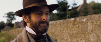 Movie still from “Far from the Madding Crowd” (2015), directed by Thomas Vinterberg – A man with a beard wearing a hat and a tie; Close Up shot, Over the shoulder angle