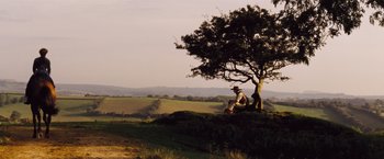 Movie still from “Far from the Madding Crowd” (2015), directed by Thomas Vinterberg – A man sitting on top of a hill next to a tree; Wide shot, Low angle