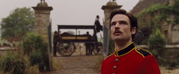 Movie still from “Far from the Madding Crowd” (2015), directed by Thomas Vinterberg – A man in a red and black uniform standing in front of a carriage; Close Up shot, Over the shoulder angle