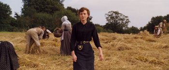 Movie still from “Far from the Madding Crowd” (2015), directed by Thomas Vinterberg – A woman standing in the middle of a field with a basket; Medium shot, Low angle