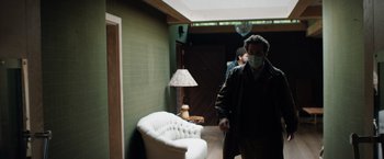 Movie still from “In the Earth” (2021), directed by Ben Wheatley – A man wearing a face mask walking in a room; Wide shot, Low angle
