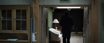 Movie still from “In the Earth” (2021), directed by Ben Wheatley – A man walking through a doorway to a living room; Wide shot, Low angle
