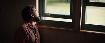 Movie still from “In the Earth” (2021), directed by Ben Wheatley – A man with a beard looking out of a window; Close Up shot, Low angle