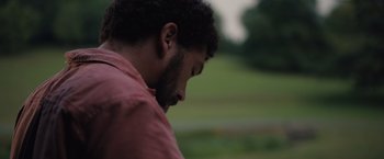 Movie still from “In the Earth” (2021), directed by Ben Wheatley – A person wearing a red shirt; Close Up shot, Low angle