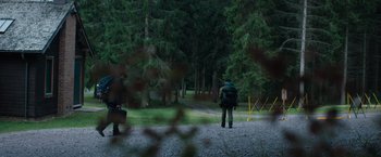 Movie still from “In the Earth” (2021), directed by Ben Wheatley – A person with a back pack is standing in the woods; Extreme Wide shot, Low angle