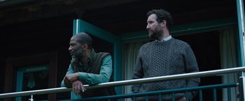 Movie still from “In the Earth” (2021), directed by Ben Wheatley – A couple of men standing next to a railing; Medium shot, Low angle