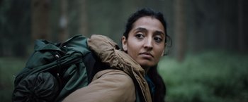 Movie still from “In the Earth” (2021), directed by Ben Wheatley – A woman with a backpack in the woods; Close Up shot, Low angle