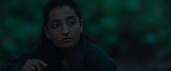 Movie still from “In the Earth” (2021), directed by Ben Wheatley – A young woman is sitting in the dark outside; Close Up shot, Over the shoulder angle