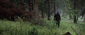 Movie still from “In the Earth” (2021), directed by Ben Wheatley – A man walking through the woods in the rain; Wide shot, Over the shoulder angle
