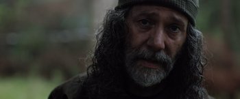 Movie still from “In the Earth” (2021), directed by Ben Wheatley – A person with long hair and a beard; Close Up shot, Over the shoulder angle