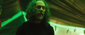 Movie still from “In the Earth” (2021), directed by Ben Wheatley – A man with long hair and a goatee is standing; Close Up shot, Low angle
